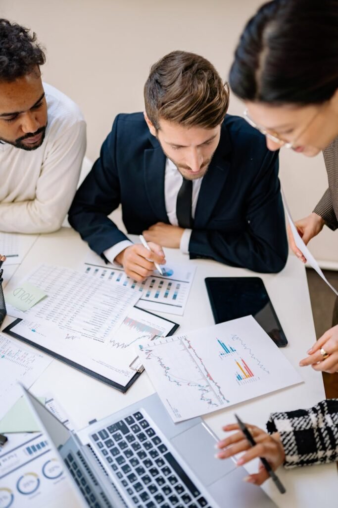 Business professionals collaborating over charts and laptops in an office.